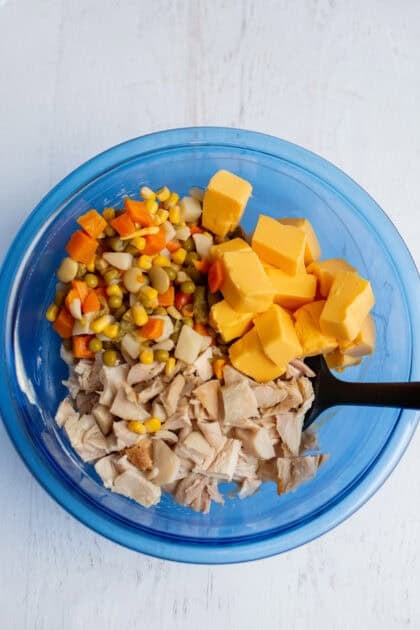 A bowl of shredded chicken, drained mixed veggies, and cubed Velveeta cheese