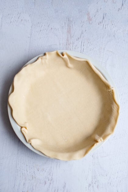 Cheesy chicken pot pie crust rolled out onto a pie plate