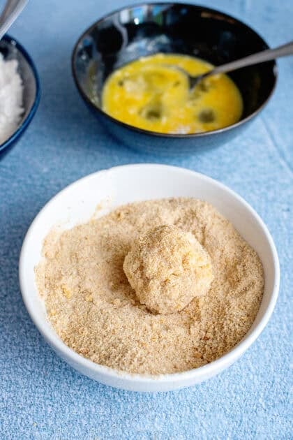 Rolling a mac and cheese ball in breadcrumbs