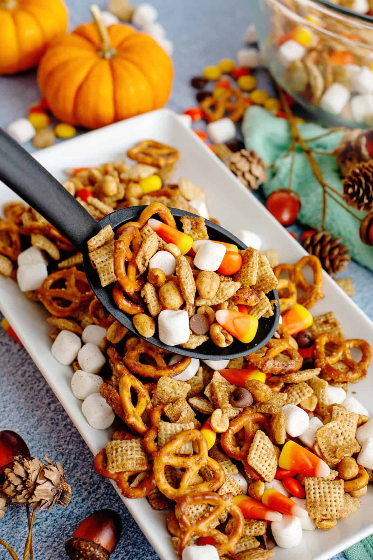 Taking a serving of fall snack mix from a large serving plate