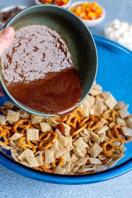 Pouring the butter mixture over the fall snack mix