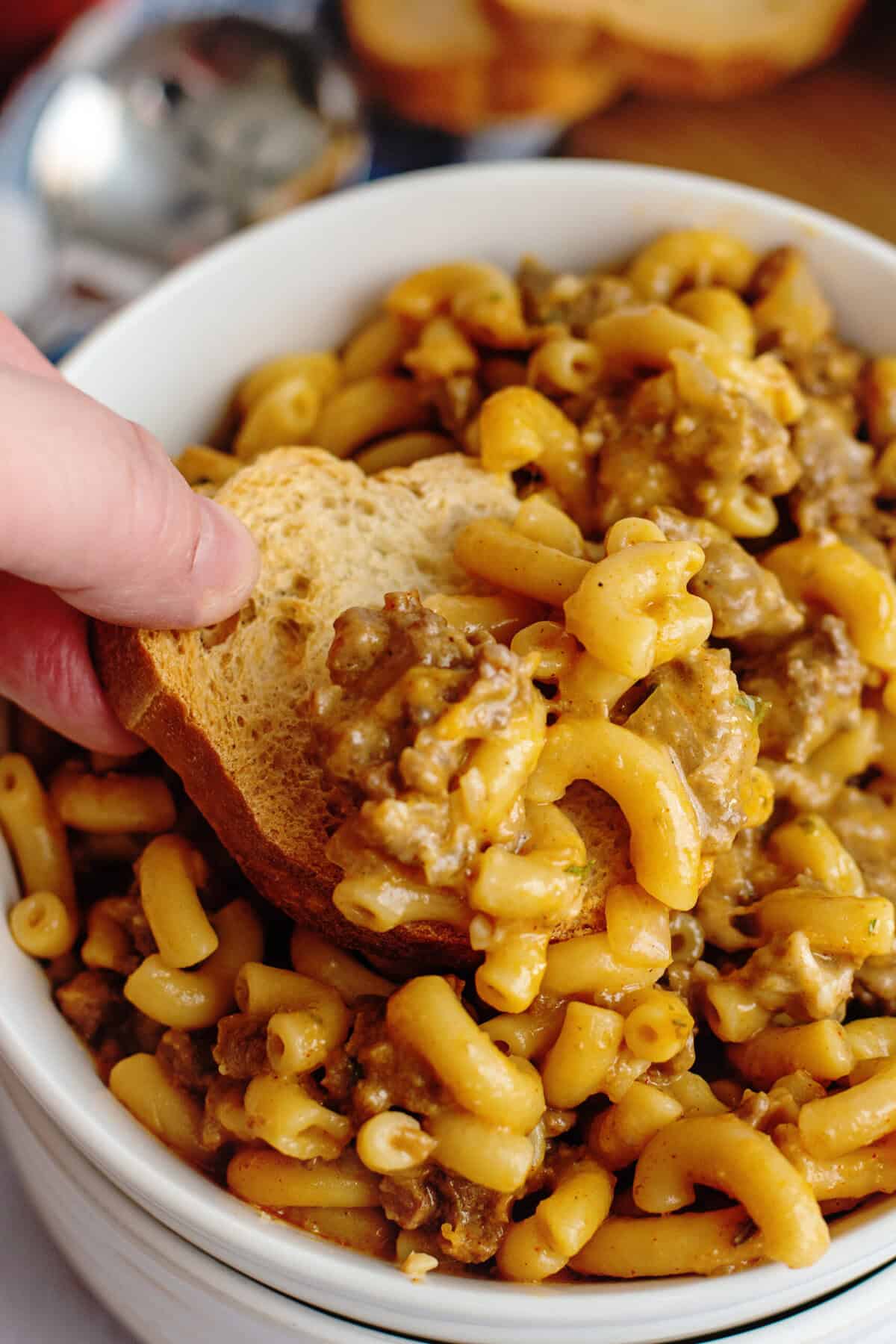 Dipping bread into a bowl of homemade hamburger helper