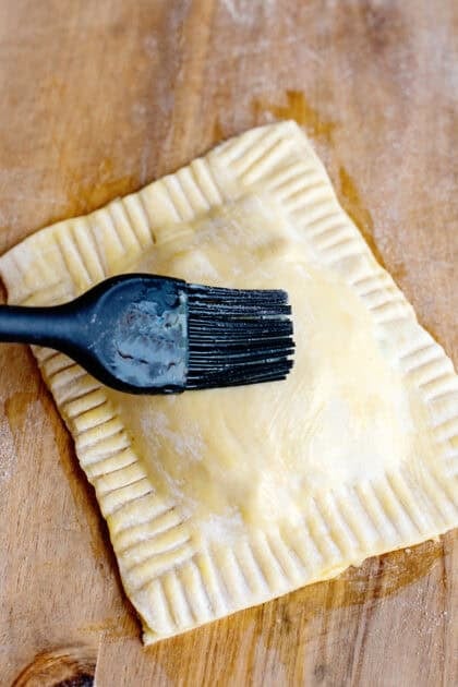 Brushing the tops of the handheld chicken pot pies with egg wash