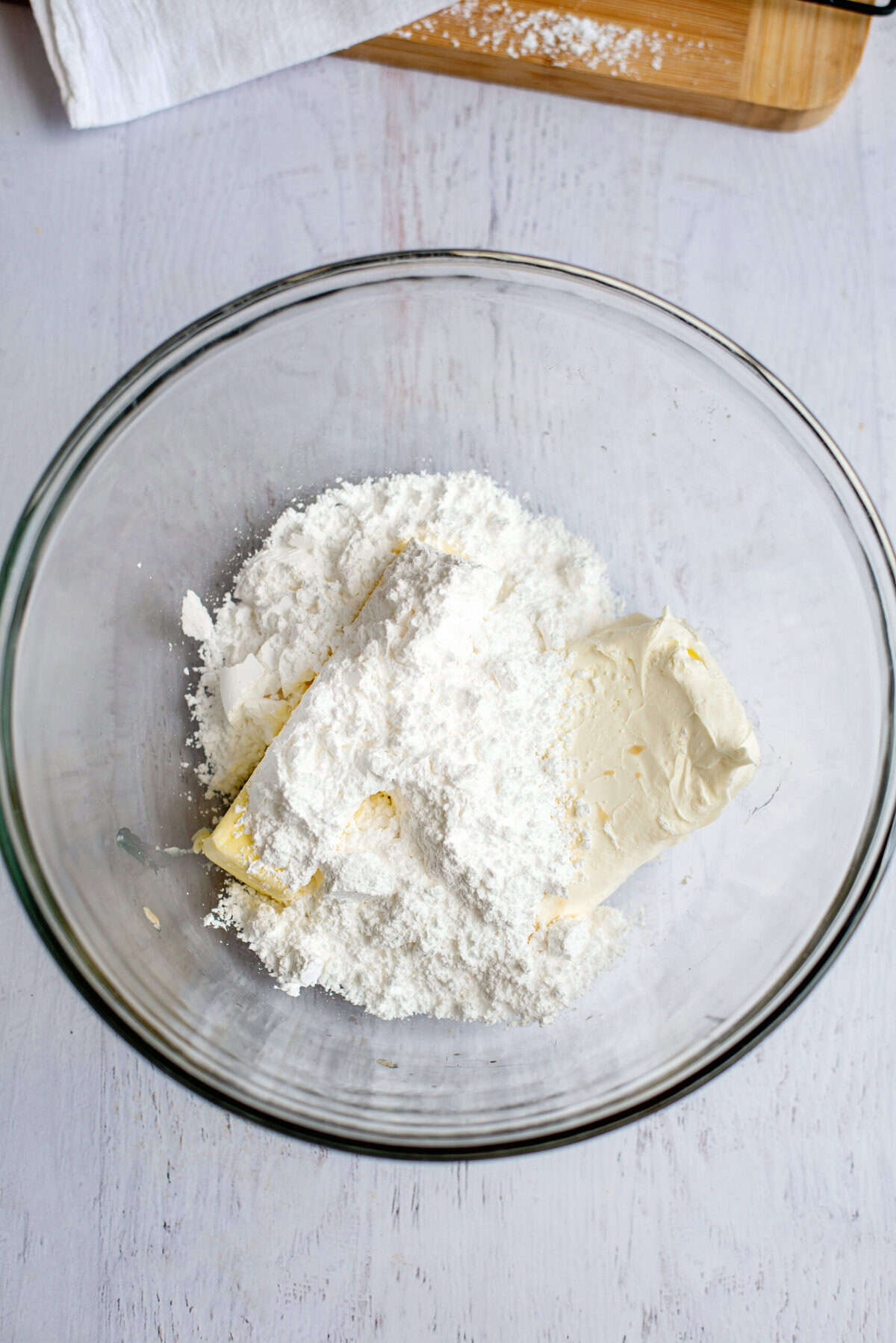 A mixing bowl with cream cheese, butter, powdered sugar, and vanilla extract