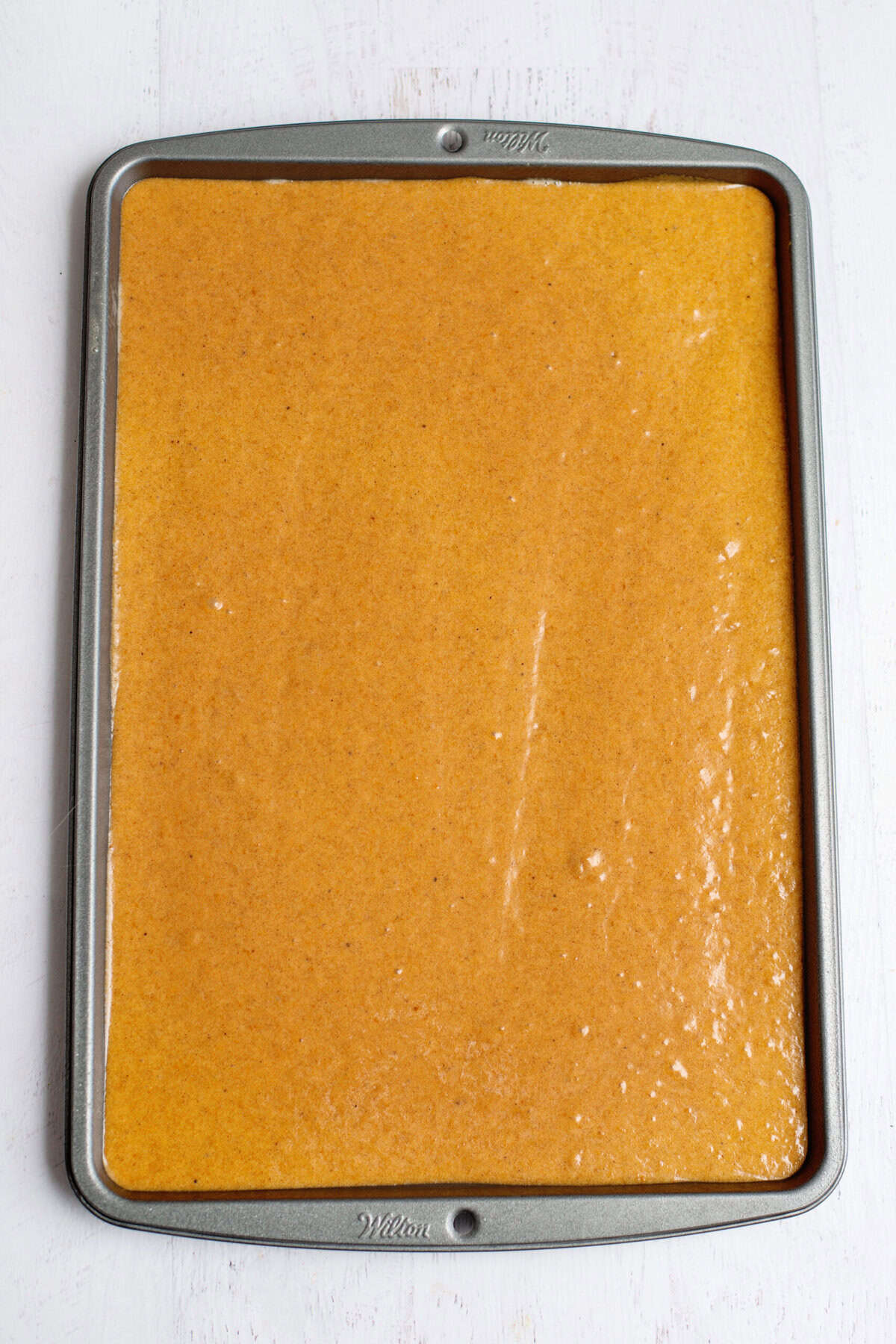 A baking pan filled with the pumpkin roll mixture