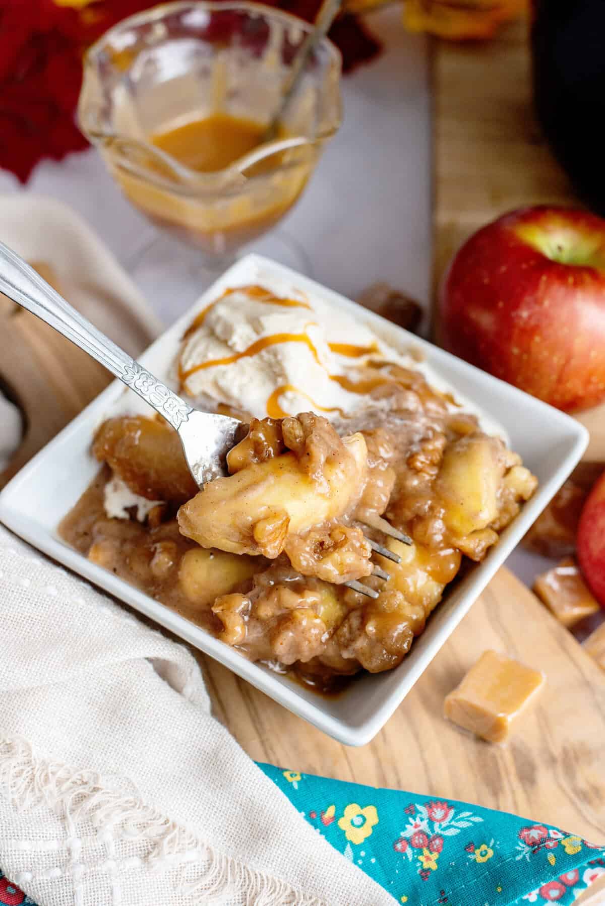 A bowl of slow cooker apple crisp with ice cream and caramel drizzle