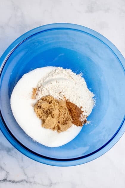 A medium mixing bowl with slow cooker apple crisp dry ingredients and spices