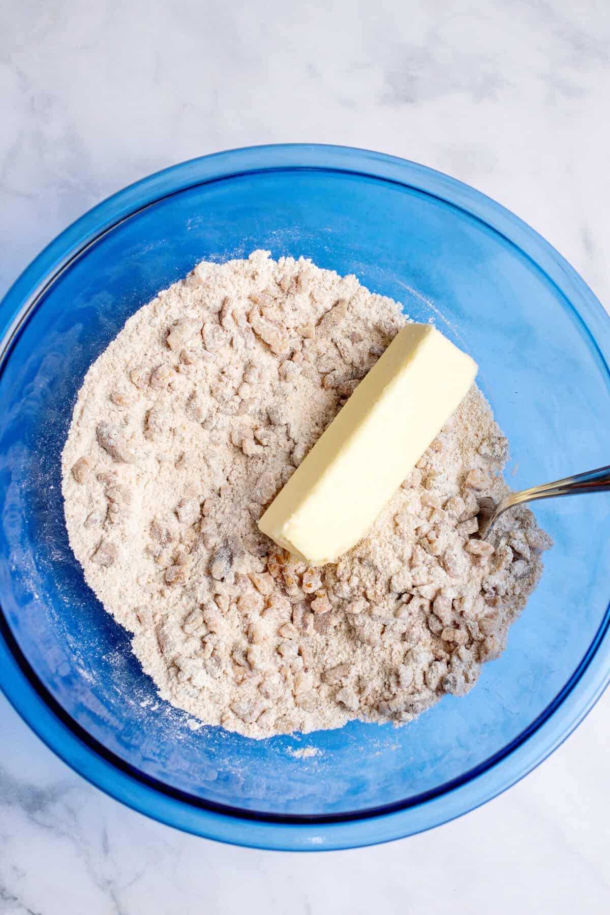 A medium bowl of stirred dry ingredients for slow cooker apple crisp with butter