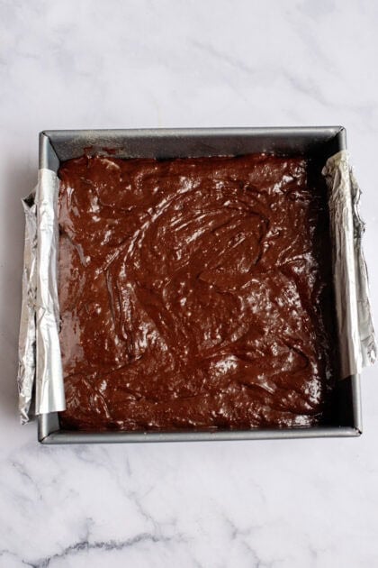 Brownie batter spread evenly across the graham crackers