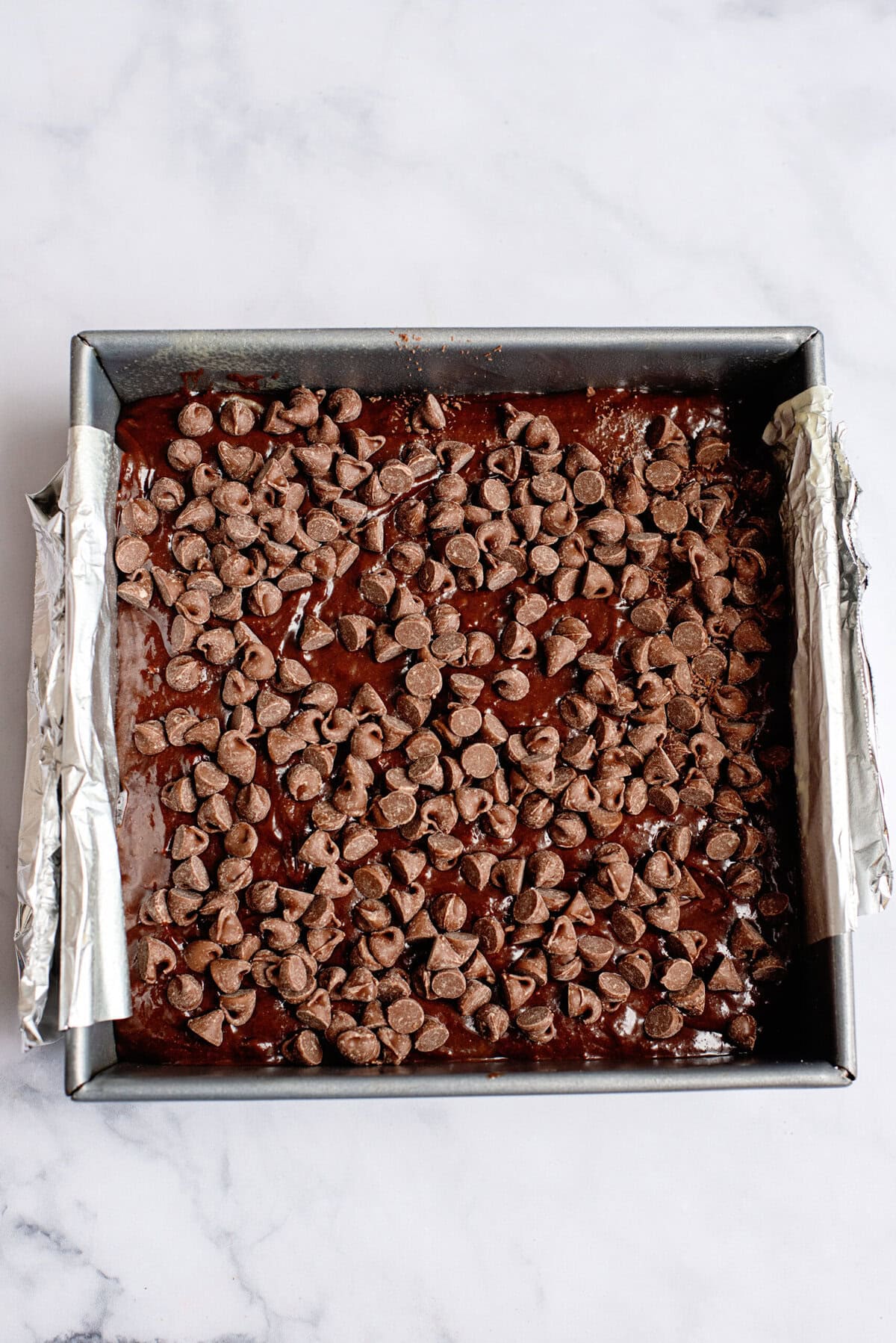 A layer of chocolate chips spread across the s'mores brownie base