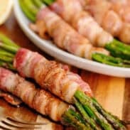 Bacon wrapped asparagus on a wooden cutting board.