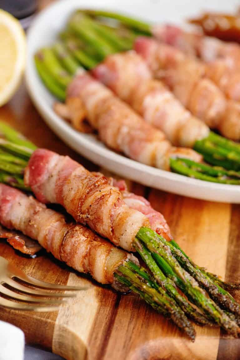 Bacon wrapped asparagus on a wooden cutting board.