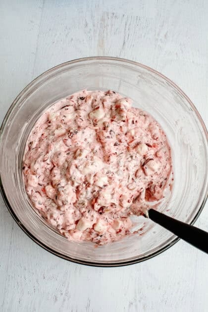 Mixing together all the ingredients for cranberry fluff salad in a bowl
