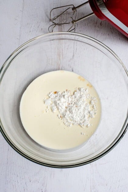 A bowl with heavy cream, powdered sugar, and vanilla extract to make the cranberry fluff salad whipped cream