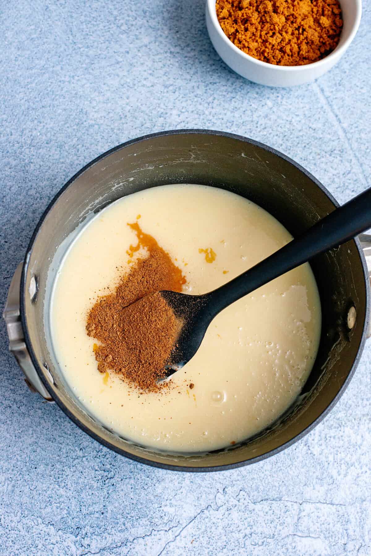 Stirring in the vanilla extract, rum extract, nutmeg, salt, and cinnamon in a saucepan