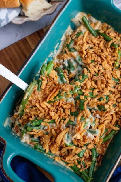 Taking a spoonful of green bean casserole from the baking dish