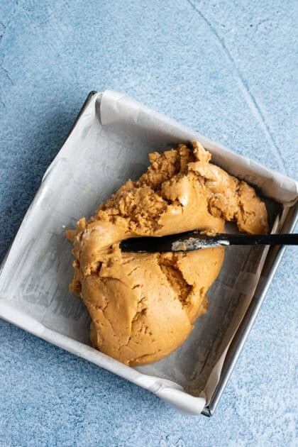 Adding peanut butter fudge mix to a baking pan