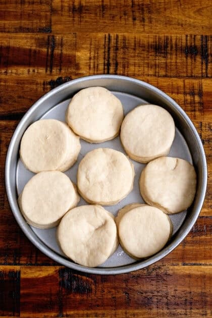 Adding raw homemade dinner rolls to a baking pan