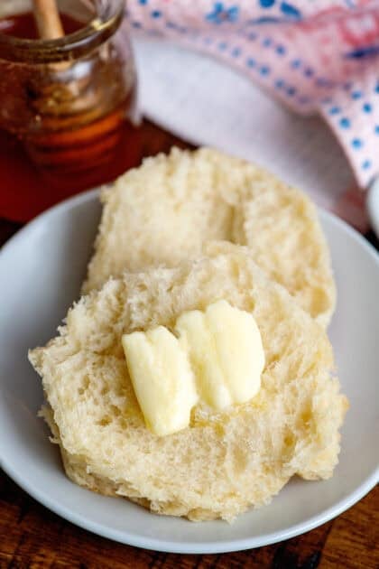 Adding butter to a halved homemade dinner roll