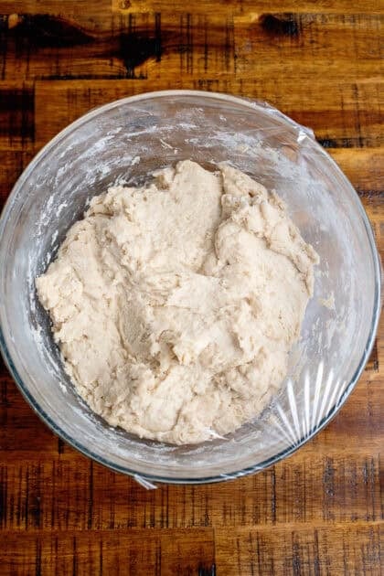 Covering the homemade dinner rolls mixture with plastic wrap