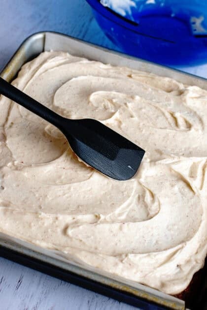 Spreading the brown butter frosting on the banana bread cake bars base