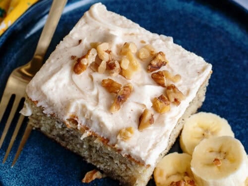 A plate with a banana bread cake bar and sliced bananas