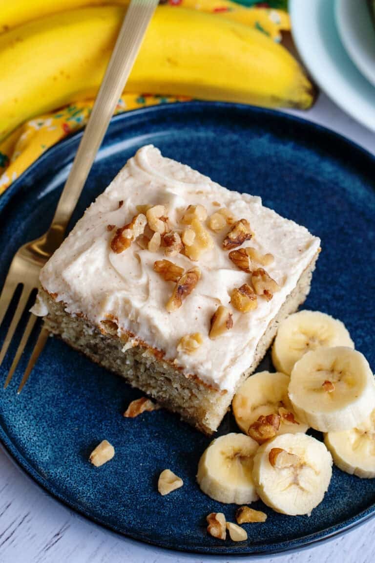 A plate with a banana bread cake bar and sliced bananas