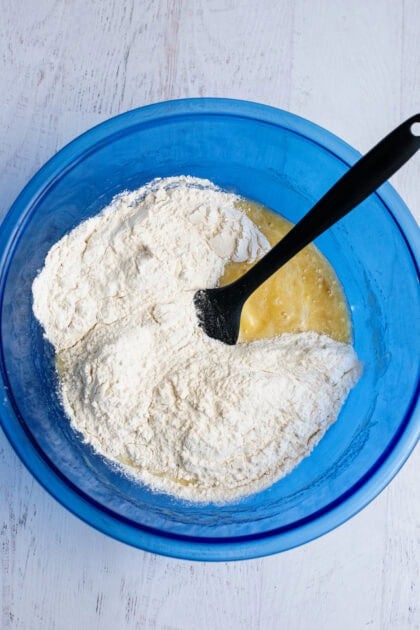 Adding dry ingredients to a bowl of wet ingredients for the banana bread cake bars