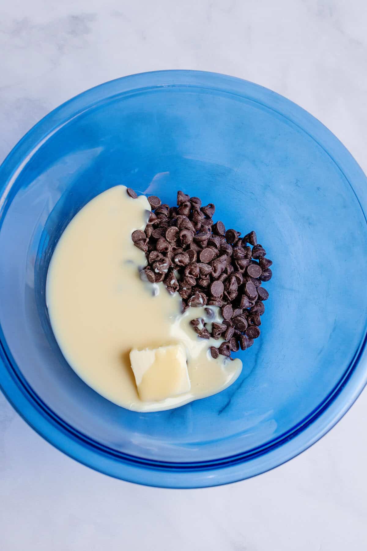 A bowl with semi-sweet chocolate chips, sweetened condensed milk, and butter