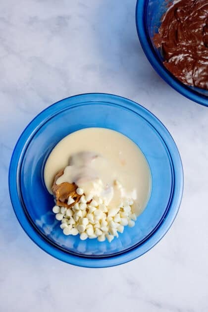 A bowl with creamy peanut butter, white chocolate chips, and sweetened condensed milk