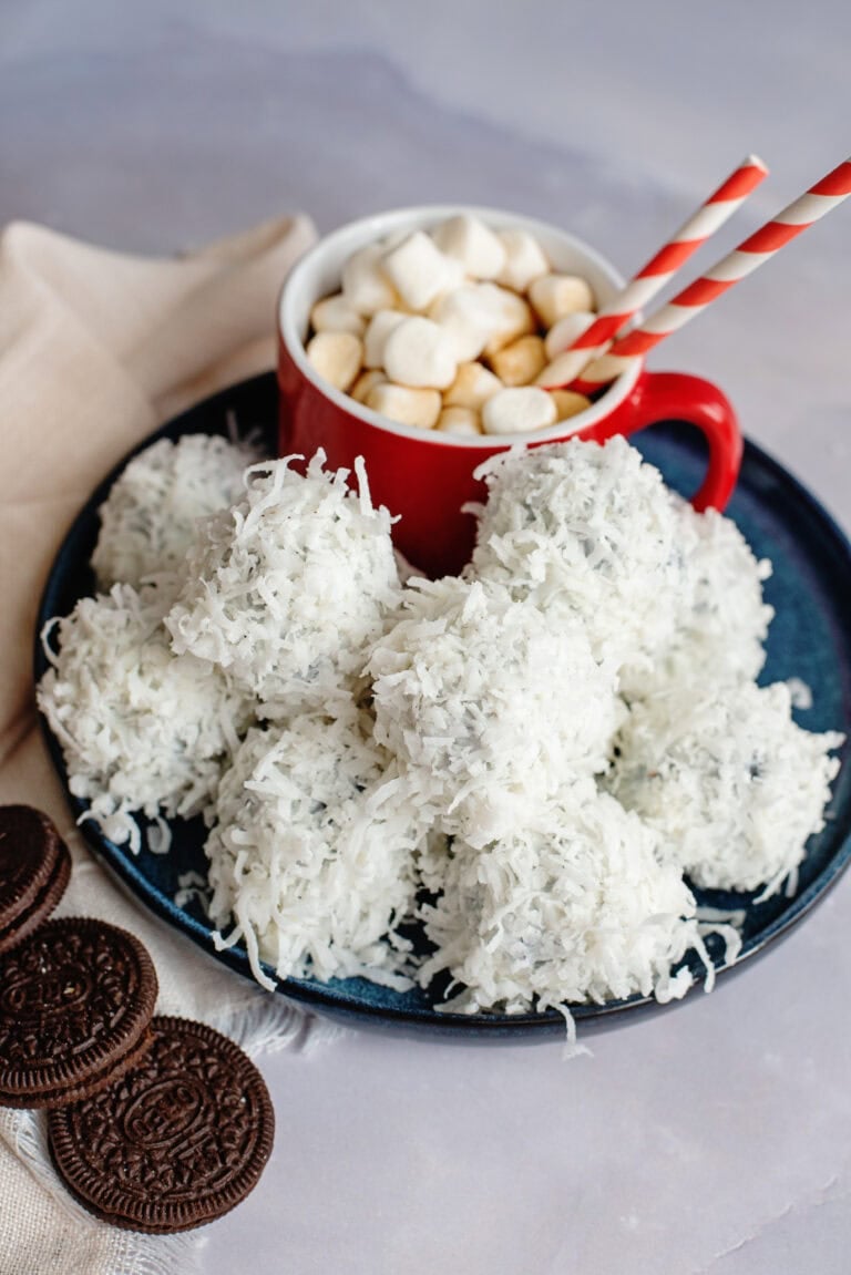 A plate of coconut-coated Oreo balls on a plate with hot cocoa