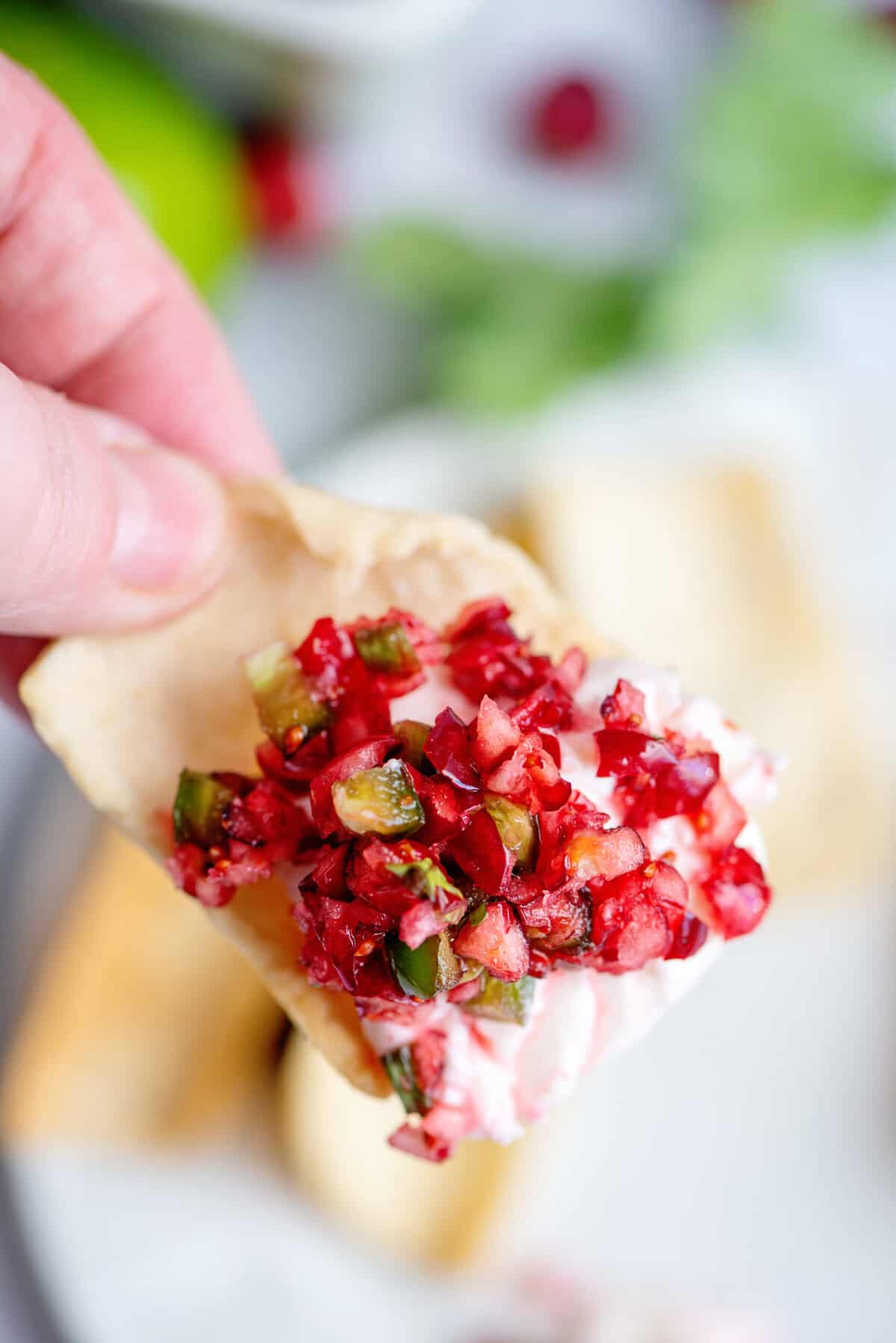 Cranberry Jalapeño Cream Cheese Dip being scooped in a chip