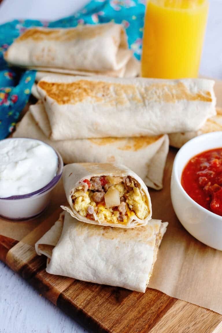 A serving tray of grab and go breakfast burritos with dip and salsa