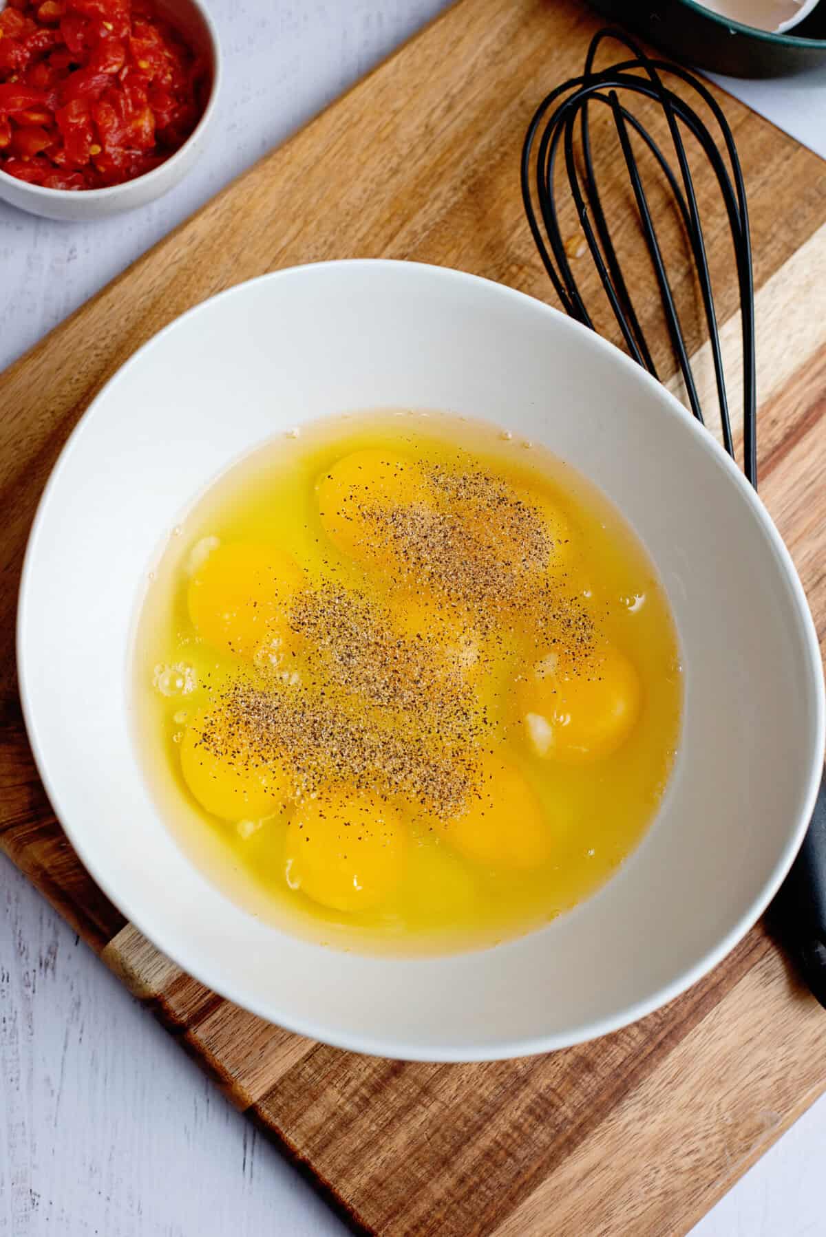 A bowl of raw eggs with pepper