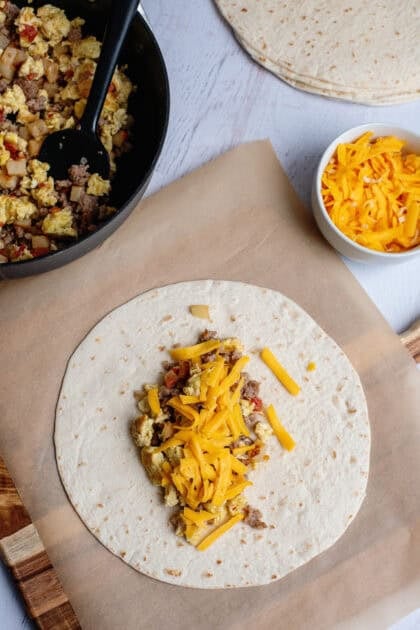 Adding the breakfast burrito filling to a tortilla