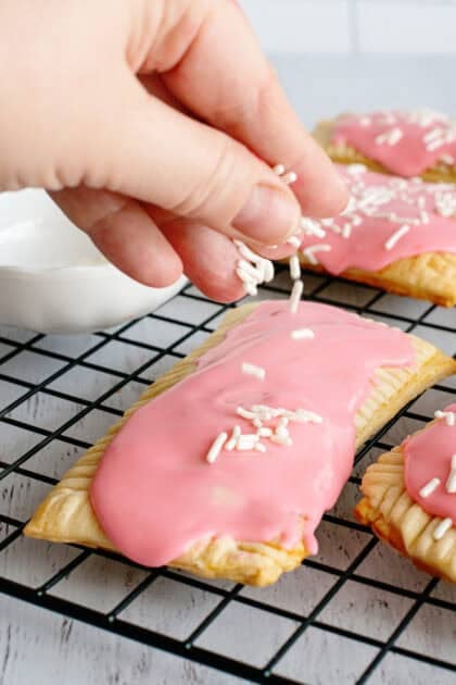 Adding sprinkles to the tops of the homemade strawberry pop-tarts