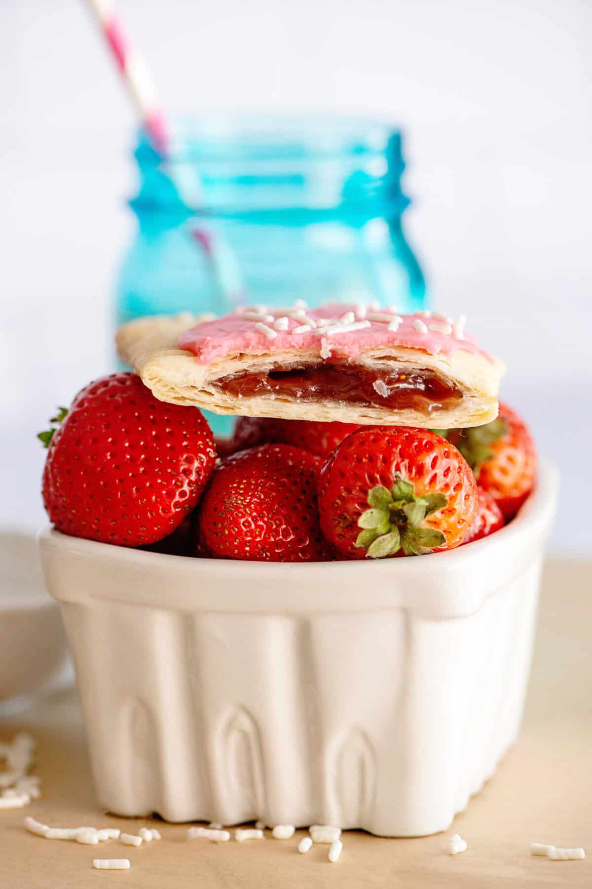 Homemade strawberry pop-tart on top of a bowl of fresh strawberries