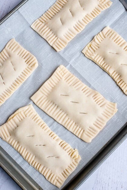Raw homemade strawberry pop-tarts on a baking sheet with holes poked on the tops