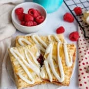 A plate of homemade toaster strudels with a bowl of raspberries