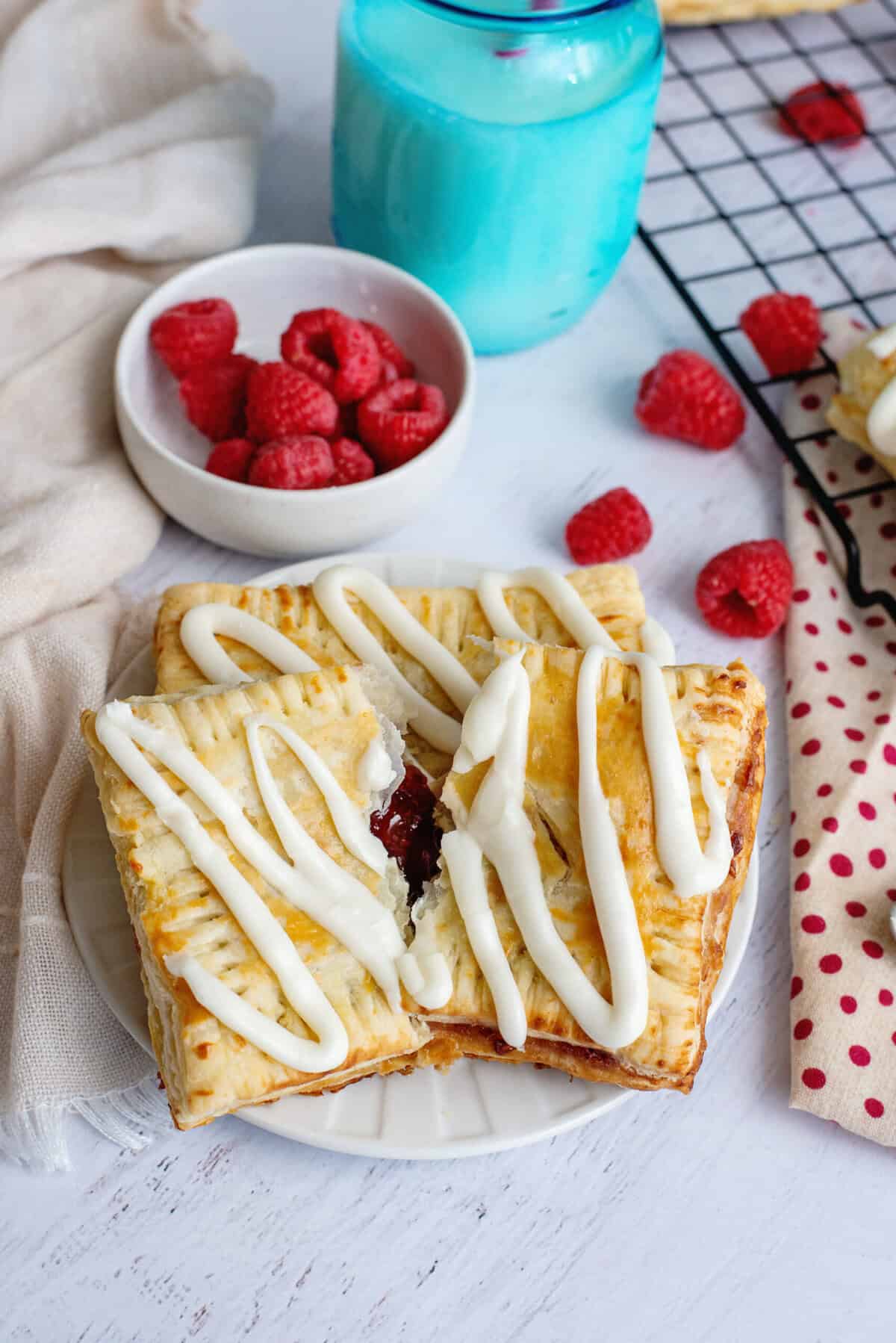A plate of homemade toaster strudels with a bowl of raspberries