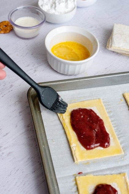 Brushing the edges of the pastry squares with egg wash