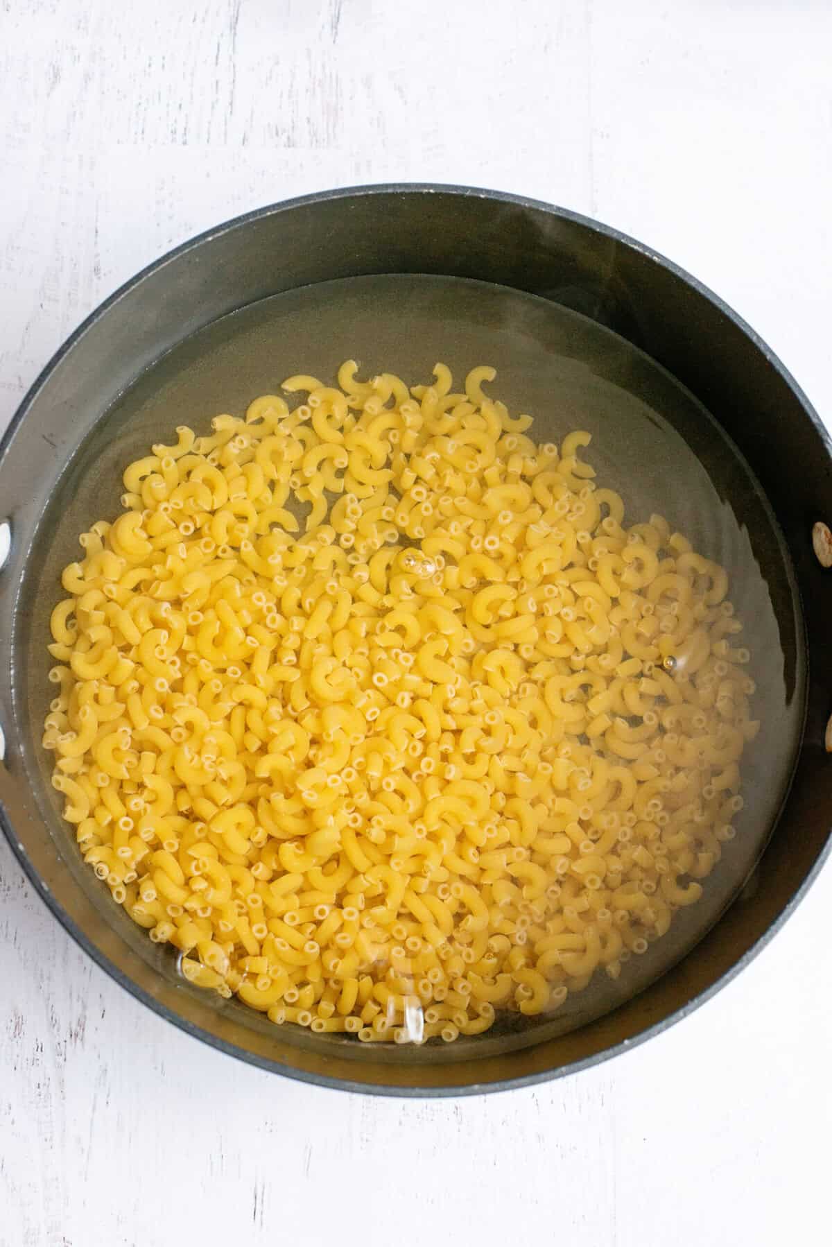 Elbow macaroni noodles in a pot of boiling water