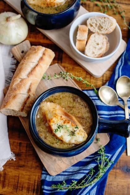 A bowl of French Onion Soup with French Baguette topping next to a baguette