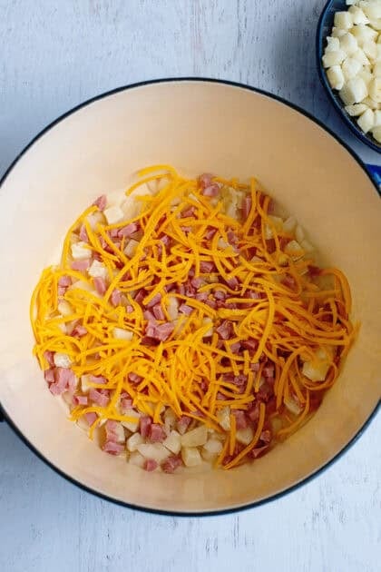 Adding onions, ham, and cheese to dutch oven