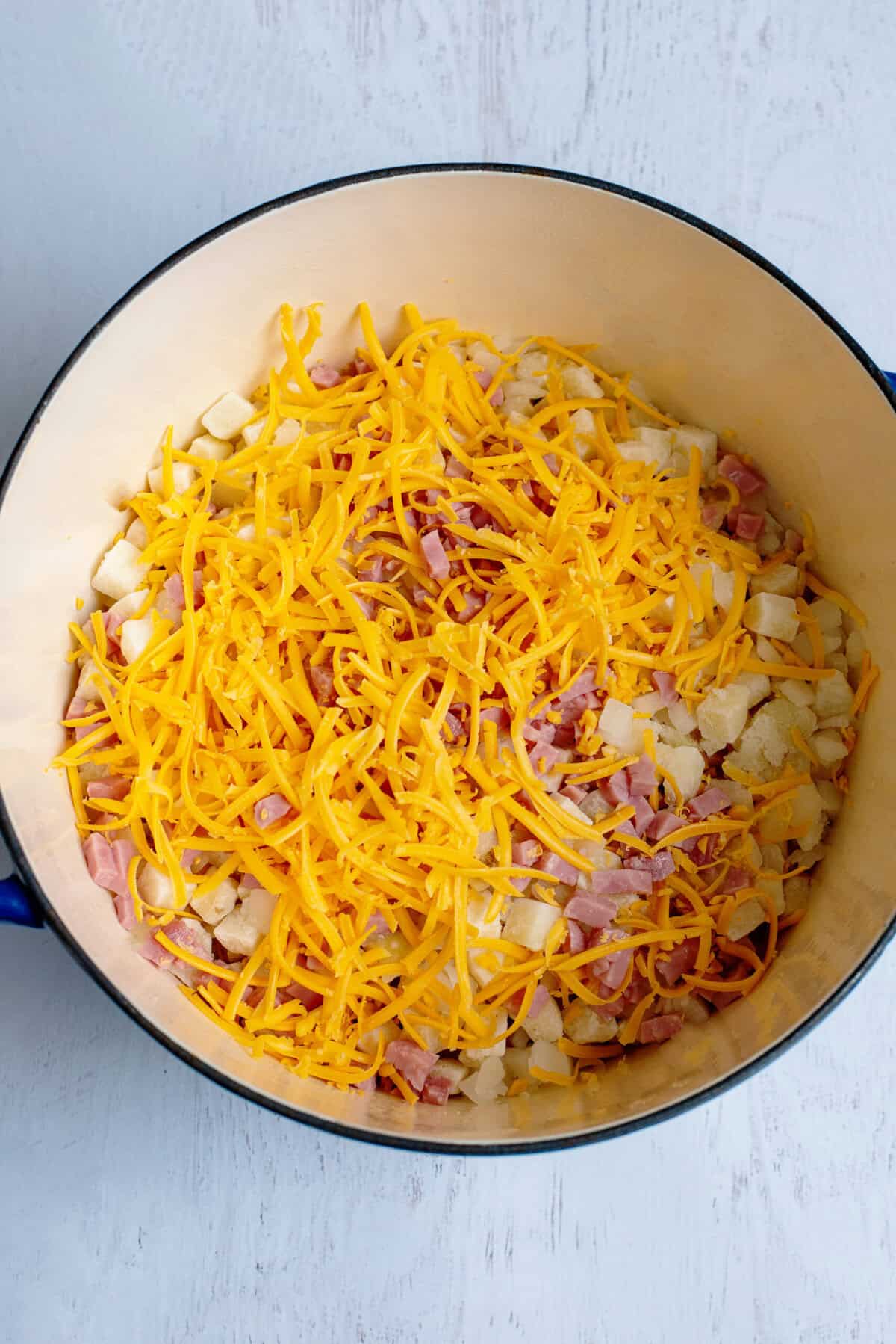 Dutch oven with ingredients for Ham, Cheese, & Egg Casserole