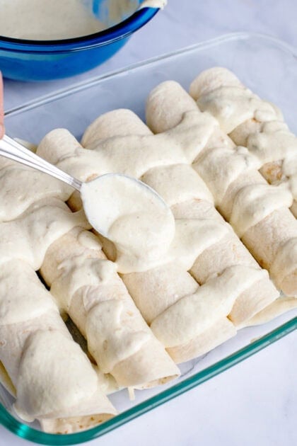 Pouring the remaining enchilada sauce on top of the Honey Lime Chicken Enchiladas