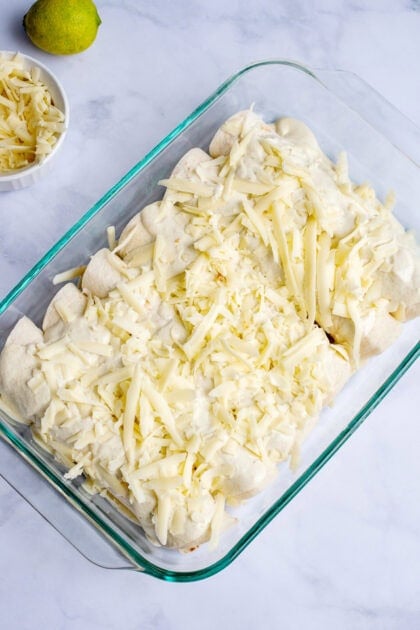 Spreading cheese on top of the Honey Lime Chicken Enchiladas 