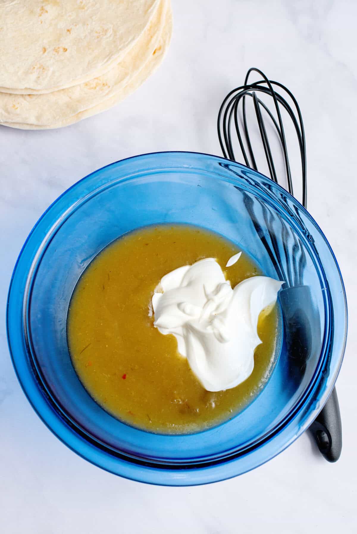 Whisking together the green enchilada sauce and sour cream in a bowl