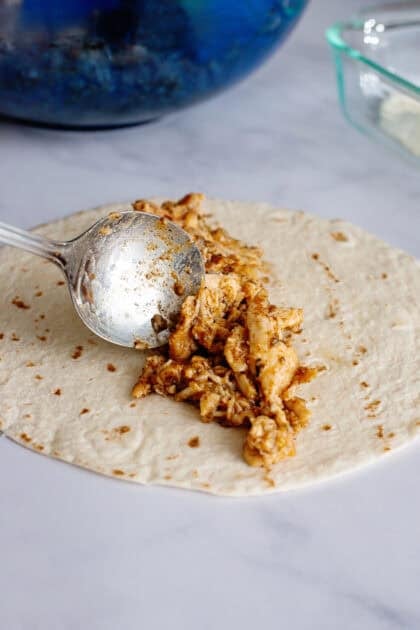 Adding chicken mixture to tortillas