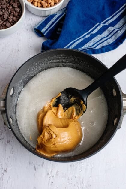Adding peanut butter to the corn syrup and sugar in pan